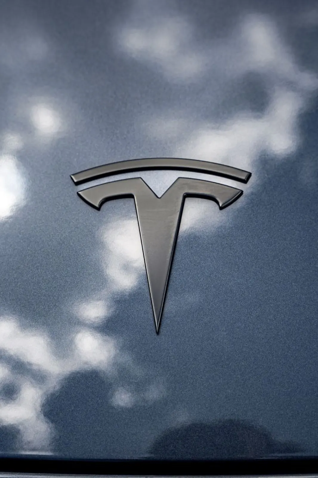 Tesla hood badge reflected in a polished finish